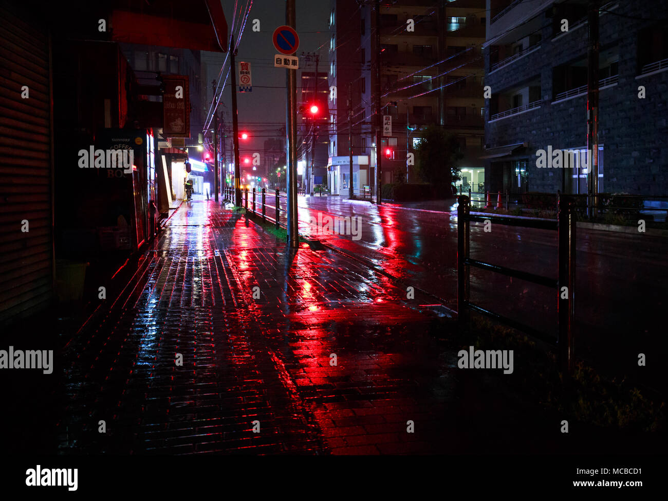 Osaka, Giappone - 14 Aprile 2018: luci rosse riflettendo su un vuoto di mezzanotte street durante una pioggia pesante Foto Stock