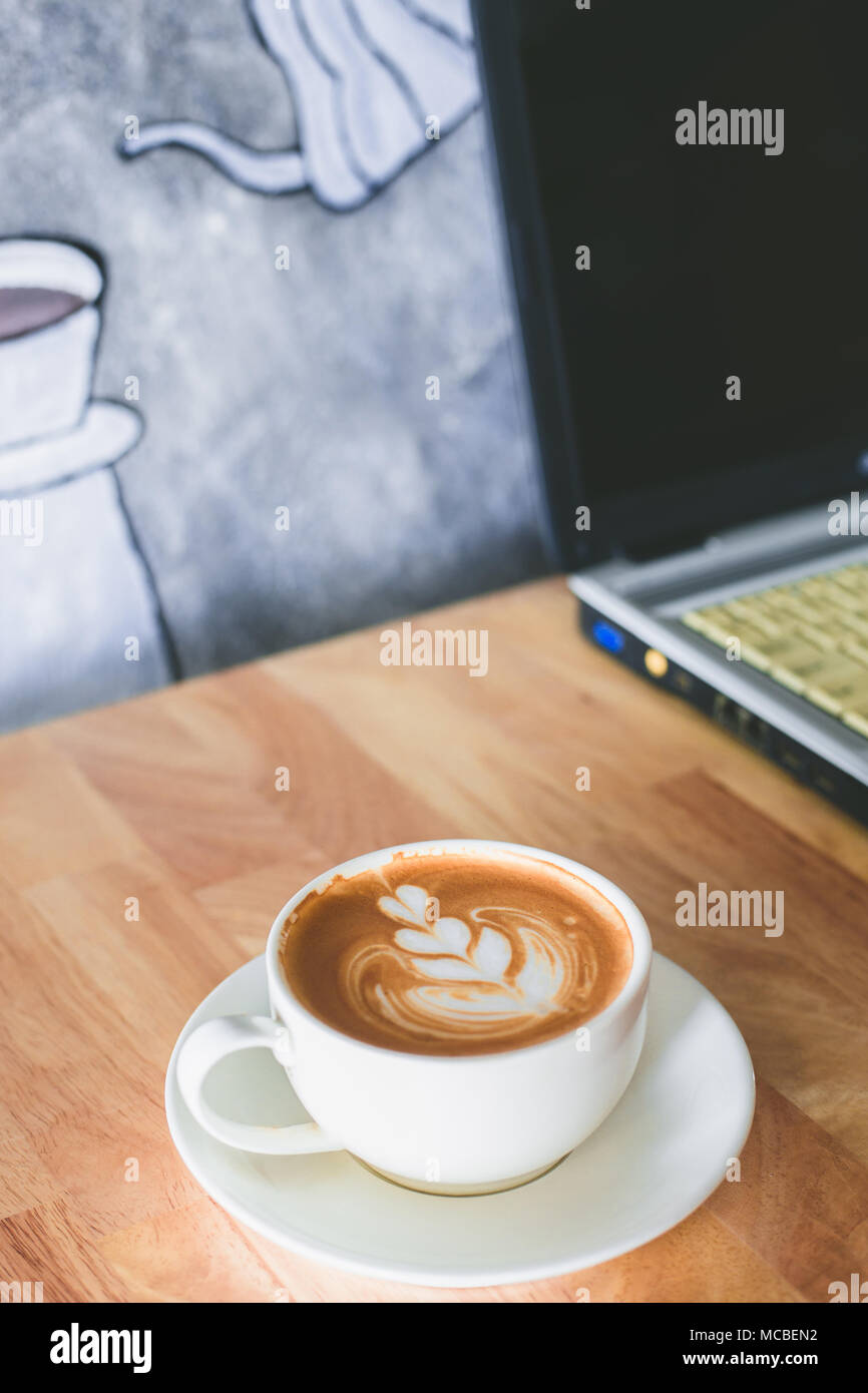 Arte a caldo latte caffè e portatile su un tavolo di legno. Foto Stock