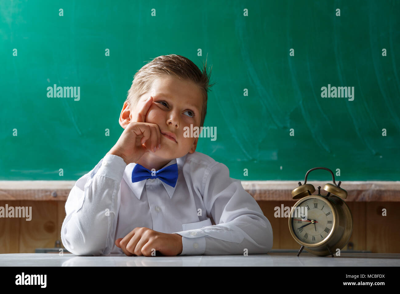 Scuola di trivellazione ragazzo con sveglia in attesa di qualcosa di Foto Stock