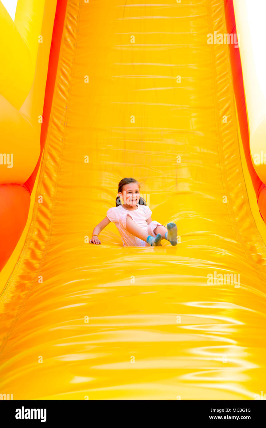 Felice bambina avente un sacco di divertimento su un castello di salto mentre lo scorrimento. Foto Stock