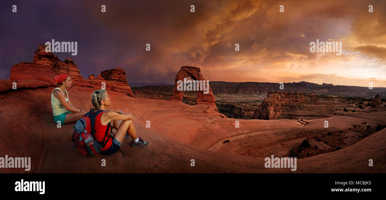 Gli escursionisti si siedono a Delicate Arch Arch, crepuscolo, Arches National Park, vicino a Moab, Utah, Stati Uniti d'America, America del Nord Foto Stock