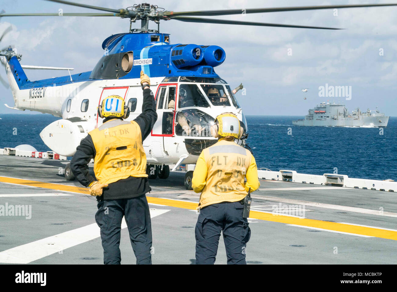 Mare delle Filippine (29 marzo 2018) di aviazione di Boatswain Mate (manipolazione) 2a classe Ian Divad, sinistra, da San Francisco e aviazione di Boatswain Mate (manipolazione) 2a classe fede Phillips, dal centro della valle, Kan., il segnale per i piloti di una SA-330 Puma elicottero, assegnato alla flotta oliatore di rifornimento USNS Tippecanoe (T-AO 199), sul ponte di volo dell'assalto anfibio nave USS Bonhomme Richard (LHD 6) durante un rifornimento in mare. Bonhomme Richard è operativo nell'Indo-Pacifico regione come parte di un regolarmente programmata di pattugliamento e fornisce una rapida capacità di risposta in caso di un regionale Foto Stock