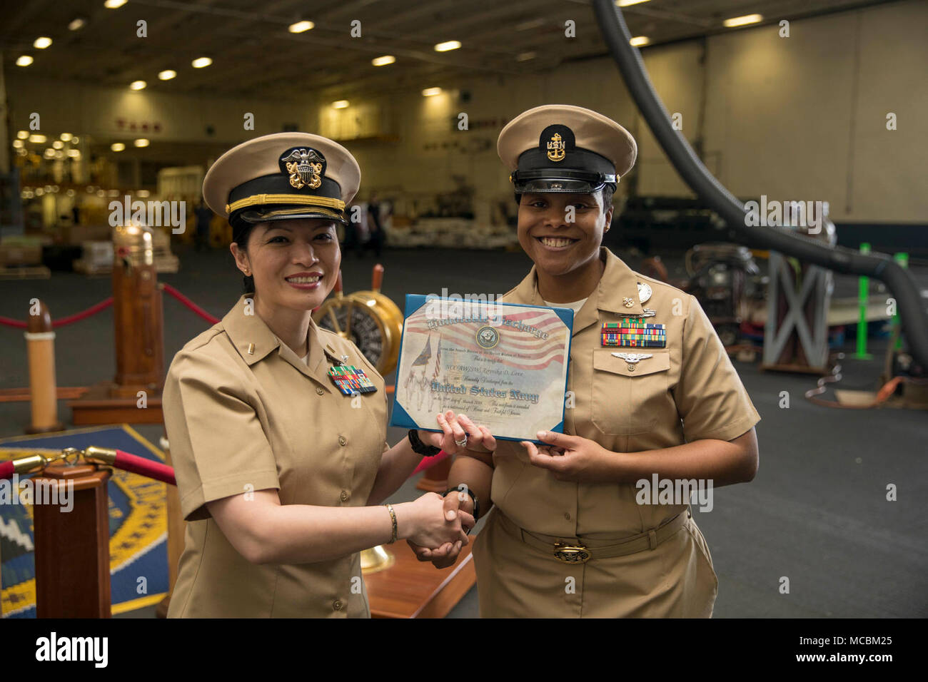 NORFOLK, Virginia (Mar. 30, 2018) -- Chief Navy Consigliere Roynika amore, assegnato alla USS Gerald Ford (CVN 78) dipartimento amministrazione, riceve un certificato di onorevoli scarica dalla Ensign Kristine Gavino, Ford personale del funzionario, durante la sua cerimonia reenlistment in nave hangar. Foto Stock