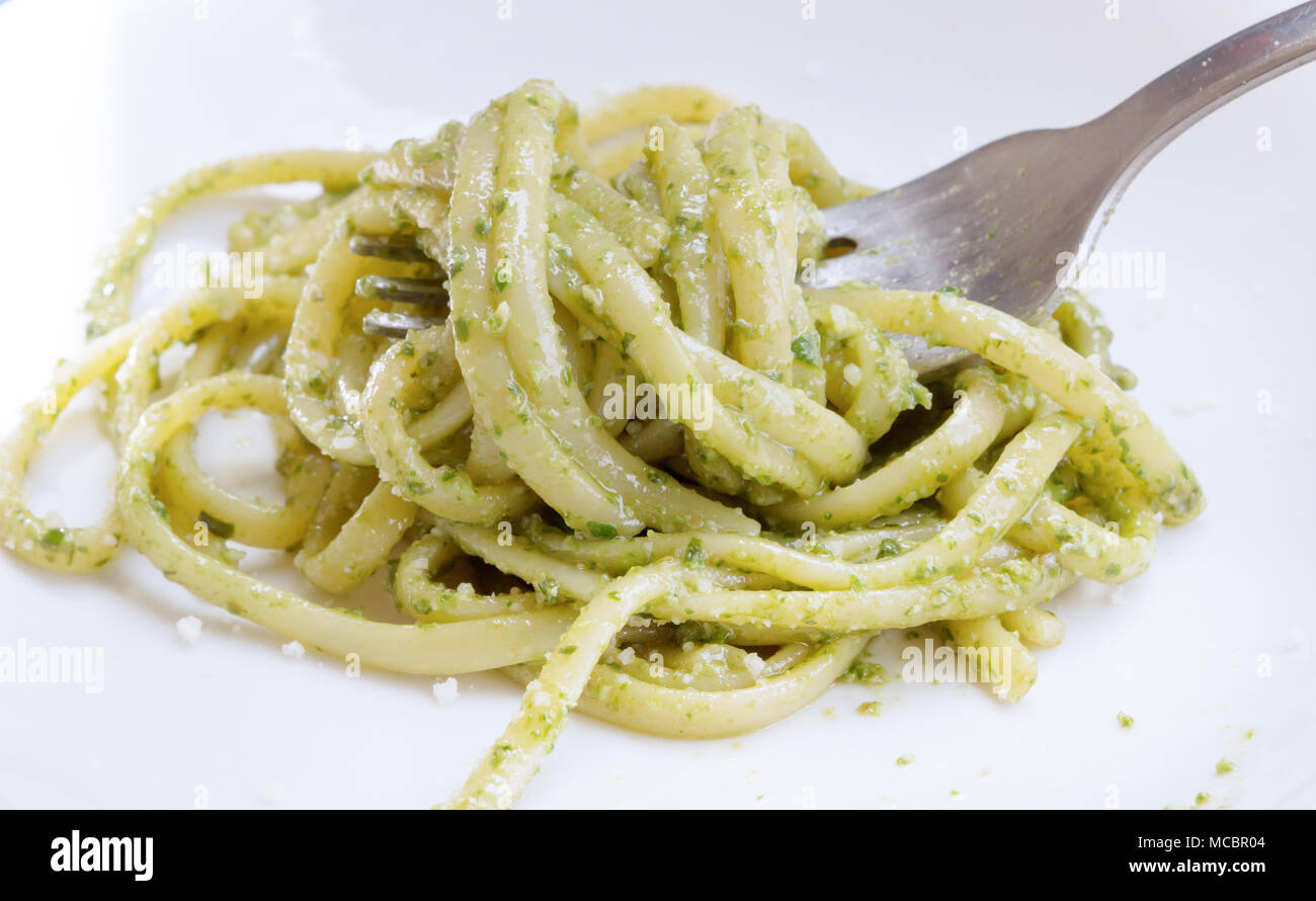 Il cibo italiano spaghetti. Spaghetti fatti in casa con il pesto e le foglie di basilico sul tavolo con la luce del sole sullo sfondo, Spaghetti con salsa verde nel Foto Stock