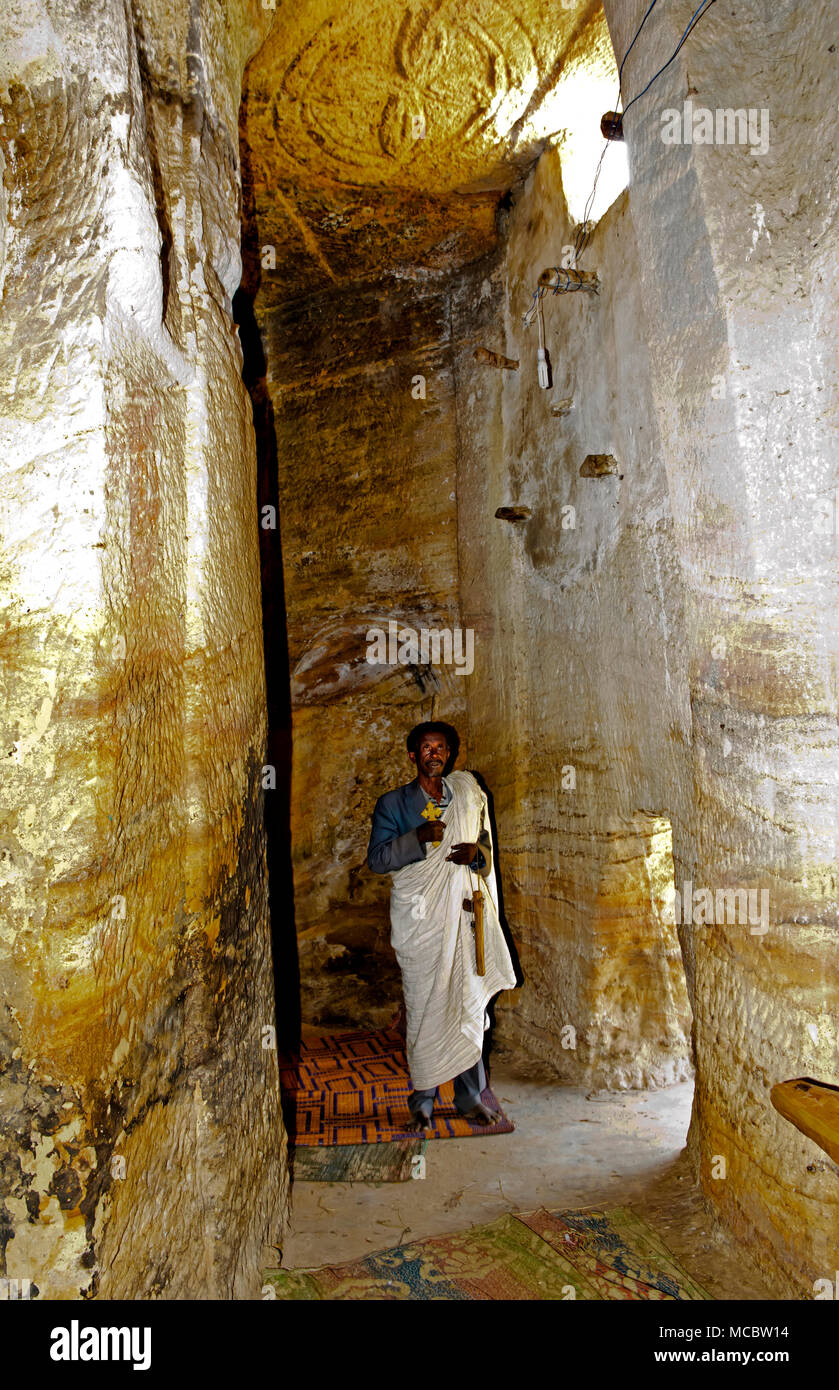 Sacerdote ortodosso in piedi all'interno di un corridoio di roccia in roccia-conci di chiesa Medhane Alem, Tigray, Etiopia Foto Stock