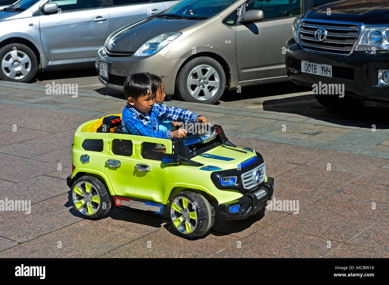 Stai cercando uno spazio per il parcheggio, bambini equitazione un elettrico Toy Cars, Ulaanbaatar, in Mongolia Foto Stock