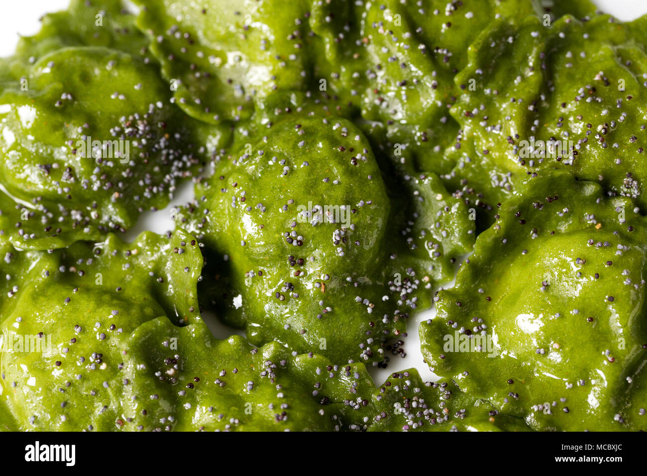 Vista dall'alto ingrandimento di una piastra di verde riempito la pasta italiana, Ravioli di spinaci con olio e semi di papavero Foto Stock