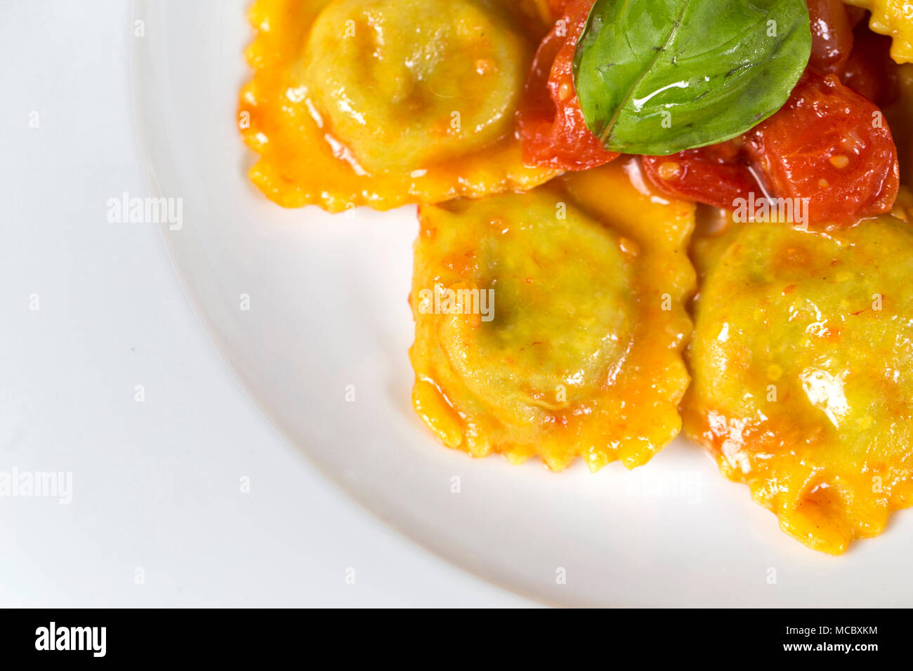 Vista superiore primo piano di un tipico piatto italiano, un piatto di ravioli con il ripieno di verdure e salsa di pomodoro e basilico sulla parte superiore Foto Stock