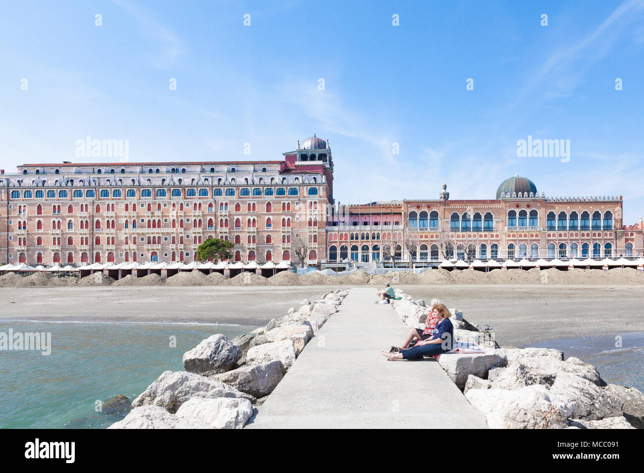 Vista lungo un molo di luzury a 5 stelle in stile moresco Excelsior Albergo, Lido di Venezia (Venezia Lido, Venezia, Veneto, Italia con donne godendo la s Foto Stock