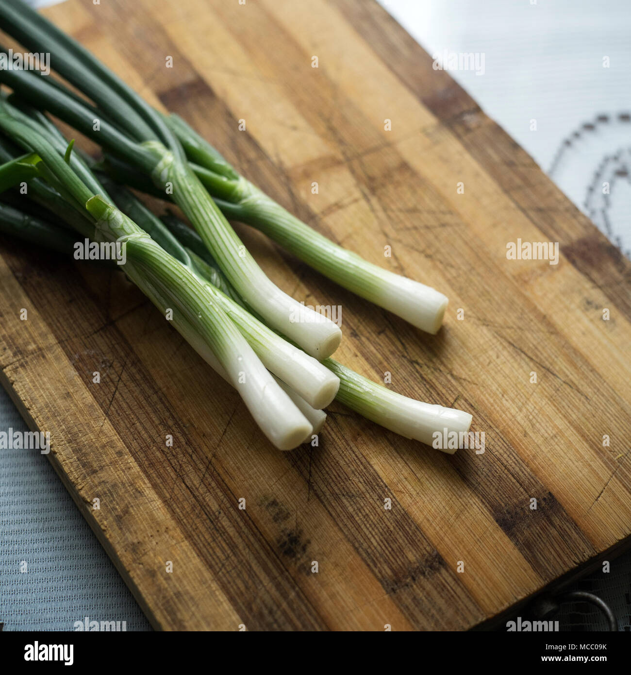 I giovani la cipolla sul tagliere sfondo Foto Stock