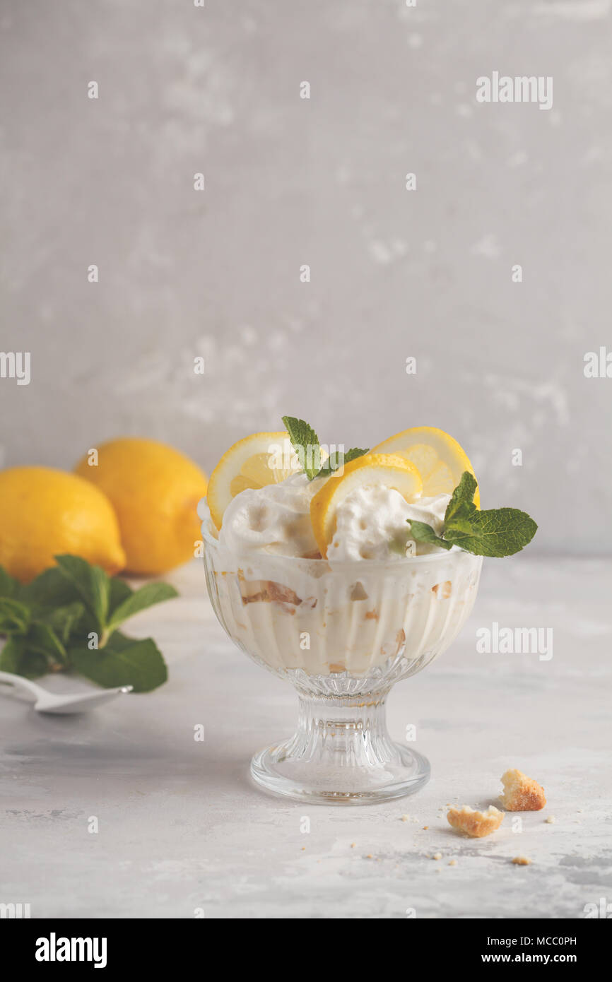 Limone dessert, limone inezia, cheesecake, panna montata, parfait. Mousse di frutta in vetro su uno sfondo luminoso. Foto Stock