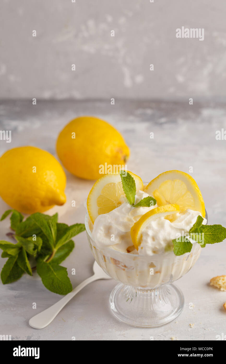Limone dessert, limone inezia, cheesecake, panna montata, parfait. Mousse di frutta in vetro su uno sfondo luminoso. Foto Stock