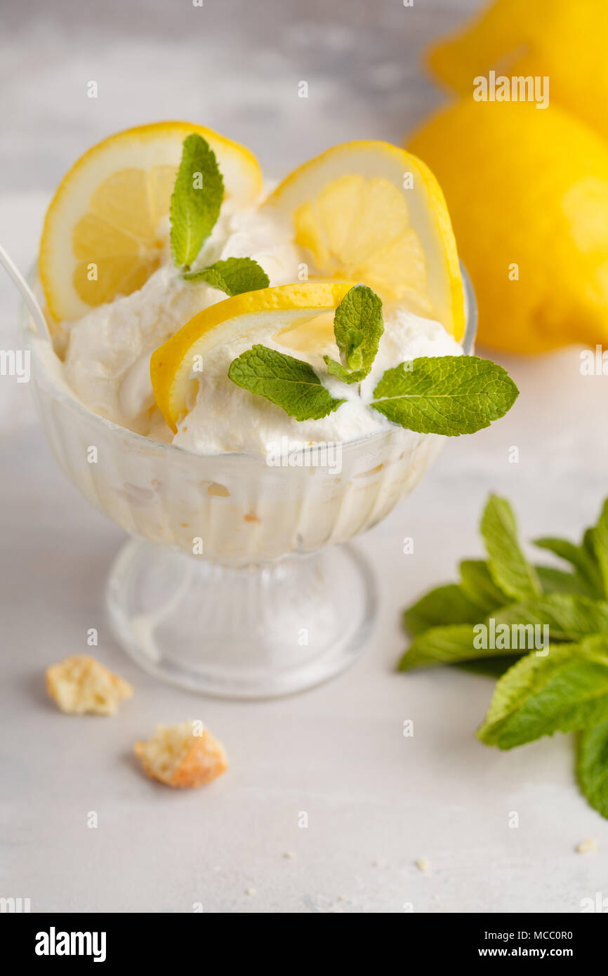 Limone dessert, limone inezia, cheesecake, panna montata, parfait. Mousse di frutta in vetro su uno sfondo luminoso. Foto Stock