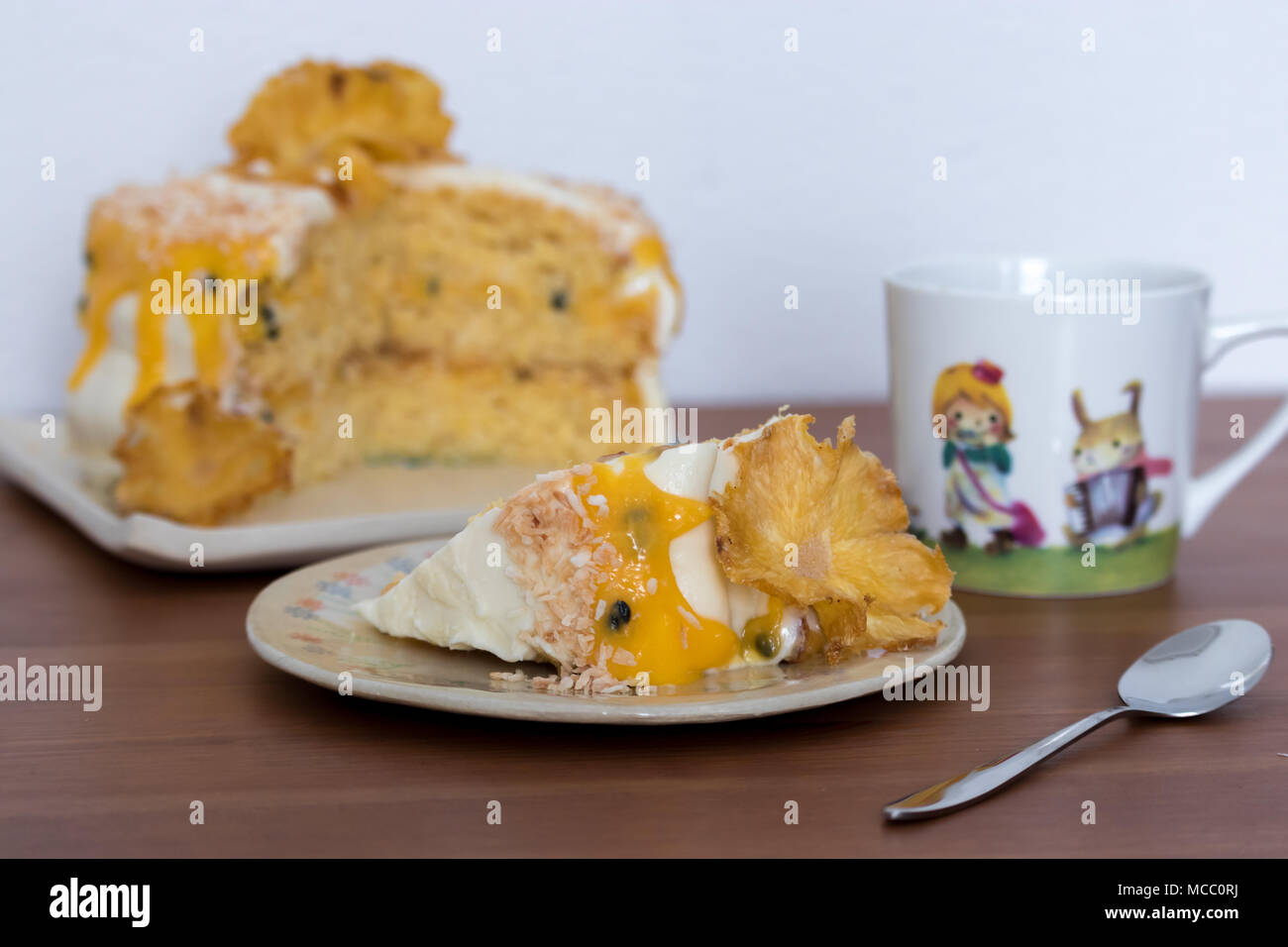 Il tè del pomeriggio. Una fetta di ananas e noce di cocco layer cake con frutti della passione cagliata. Servita su piatti fatti a mano. Foto Stock