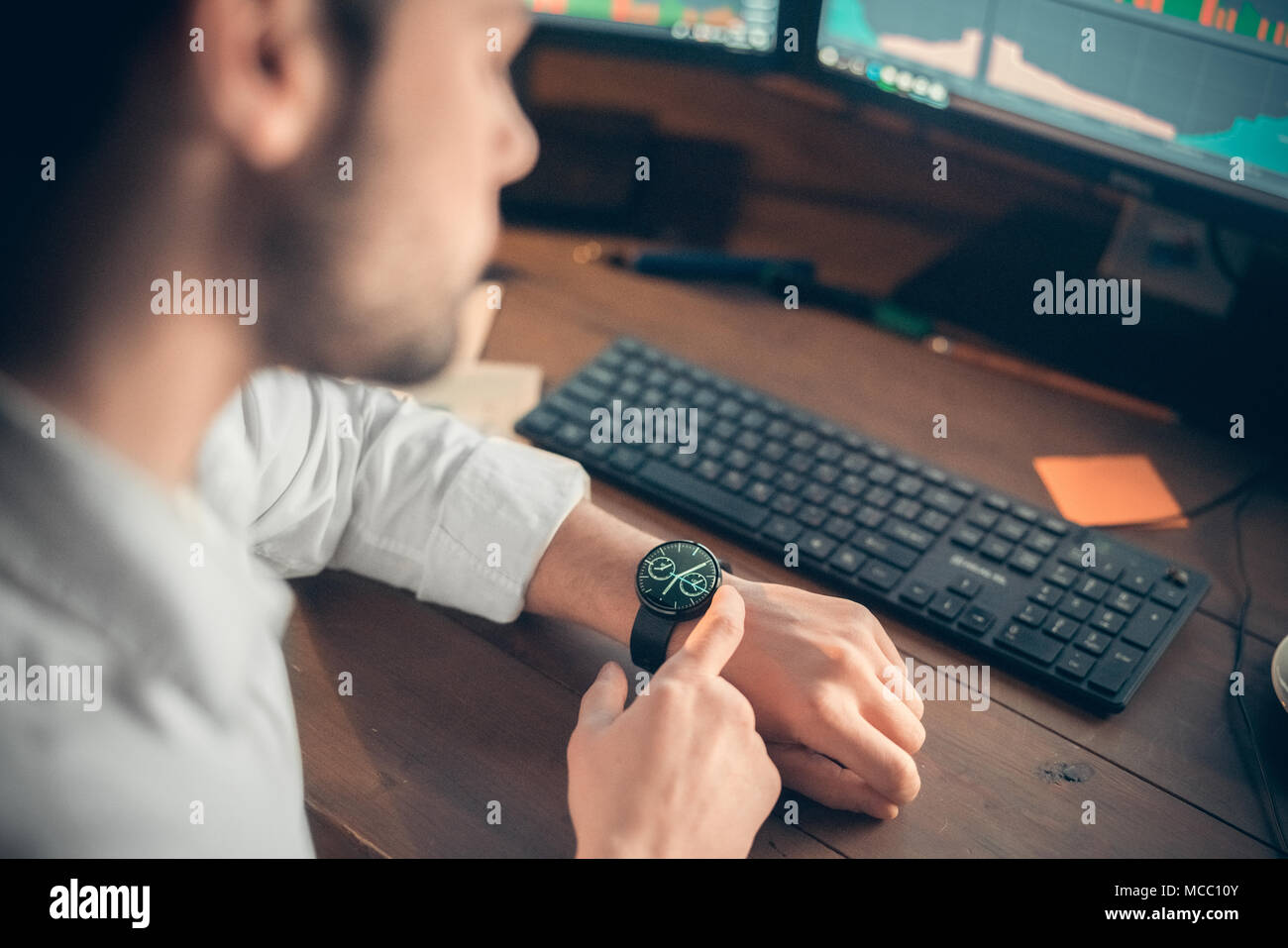 Impostazione di imprenditore innovativi e moderni smartwatch lavorando sul computer in ufficio, giovane guardando digital smart guarda il tempo di controllo o utilizzando busine Foto Stock