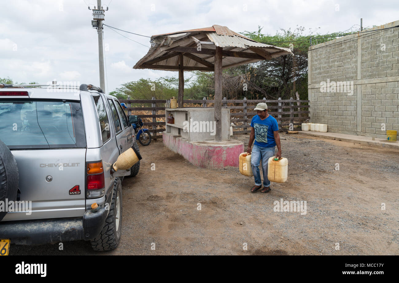 Un uomo porta due brocche di benzina per riempire un'auto in una zona rurale petro station. La Colombia, Sud America. Foto Stock