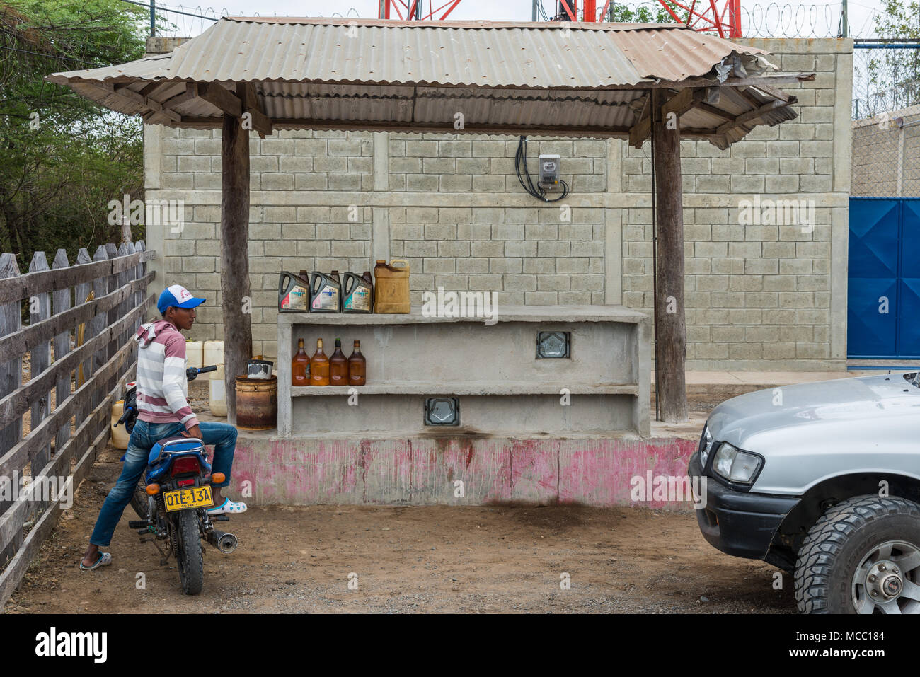 Un uomo sulla sua motocicletta in corrispondenza di una zona rurale petro station. La Colombia, Sud America. Foto Stock