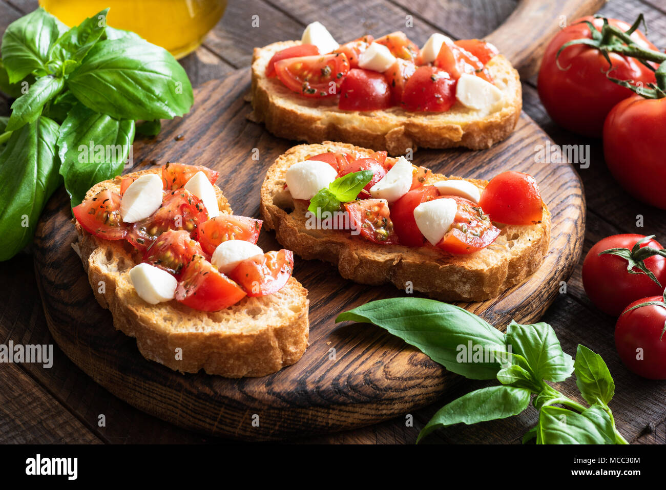 Bruschetta con pomodoro, basilico e mozzarella su tavola di legno. Italiano tradizionale di un aperitivo o uno snack, antipasto Foto Stock