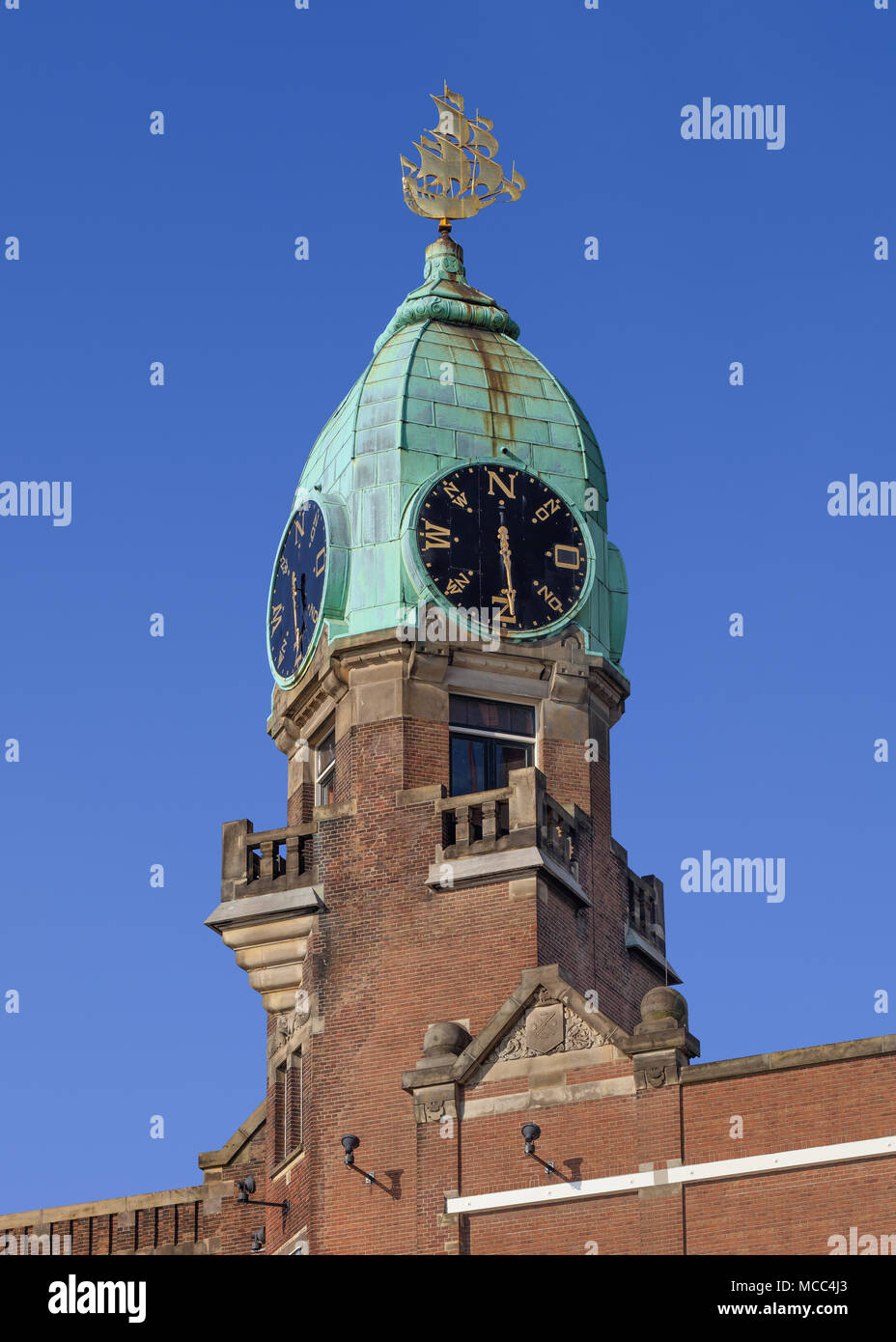 Rame ricoperto la torretta con un orologio in un classico edificio di mattoni Foto Stock