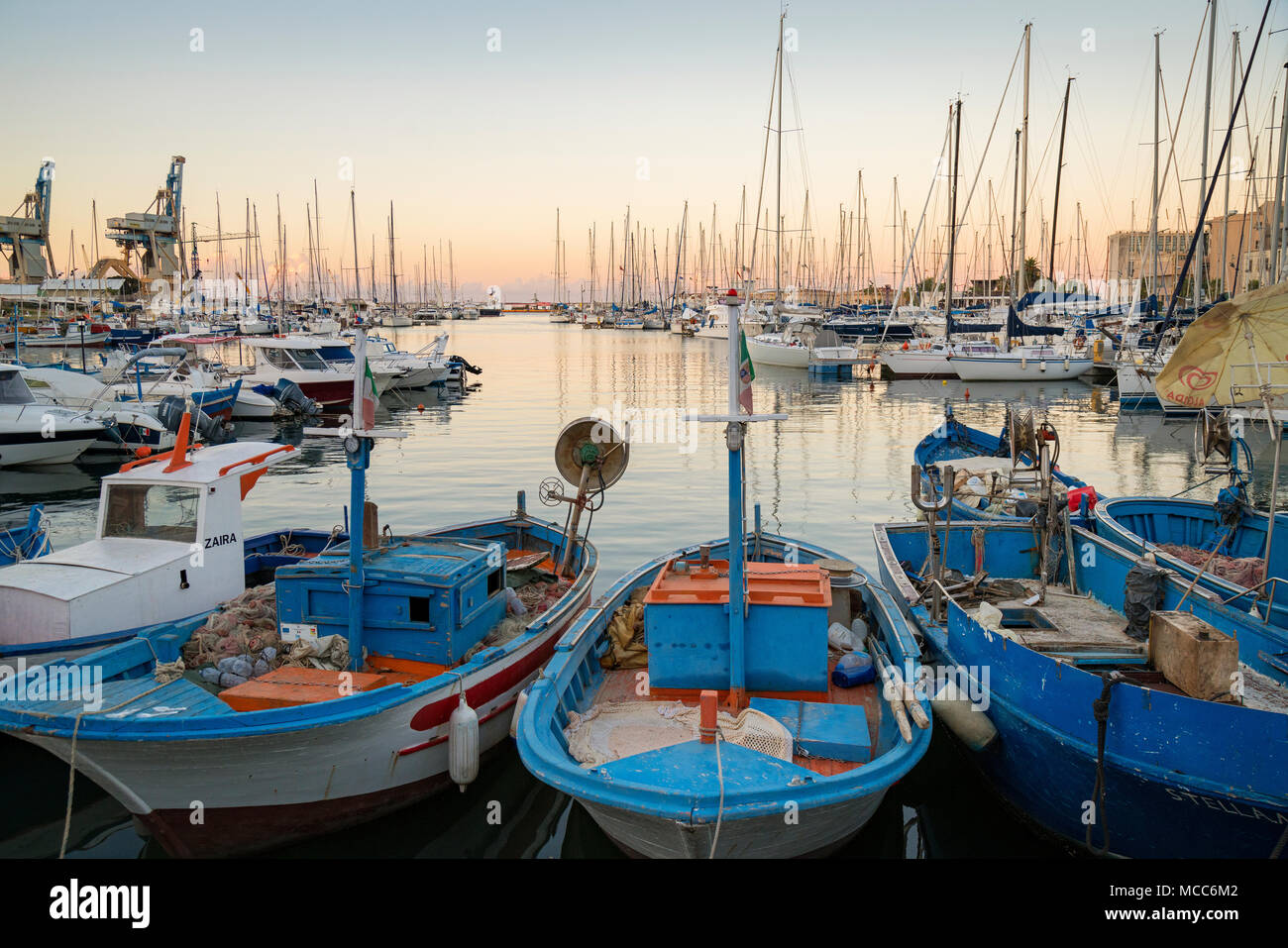 Vecchie barche da pesca e yacht moderno nel vecchio "La Cala" porto e marina a Palermo, Sicilia, Italia, mentre il sole tramonta su una giornata d'estate in agosto. Foto Stock