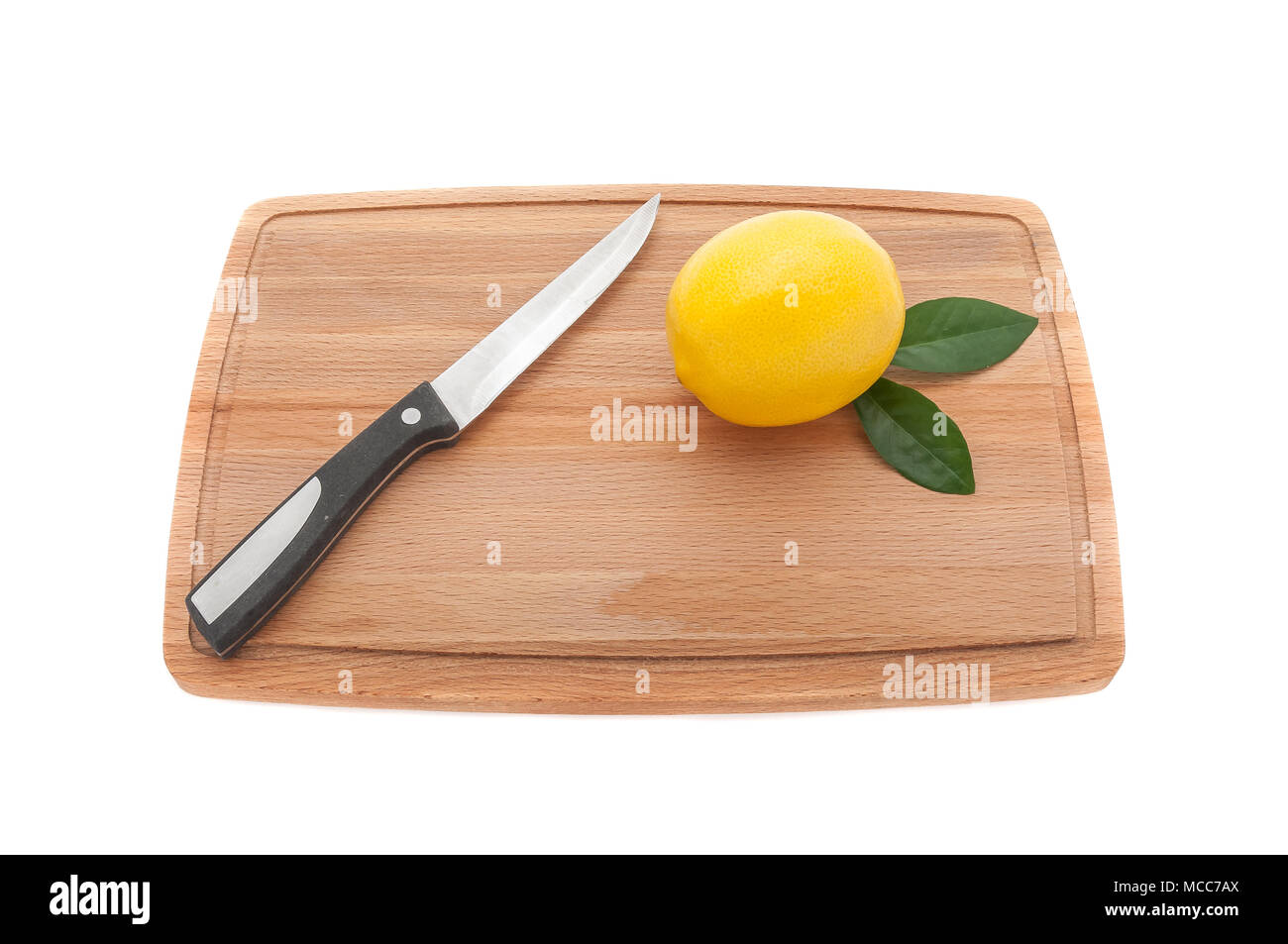 Giallo limone con foglie verdi e un coltello su una cucina in legno c Foto Stock