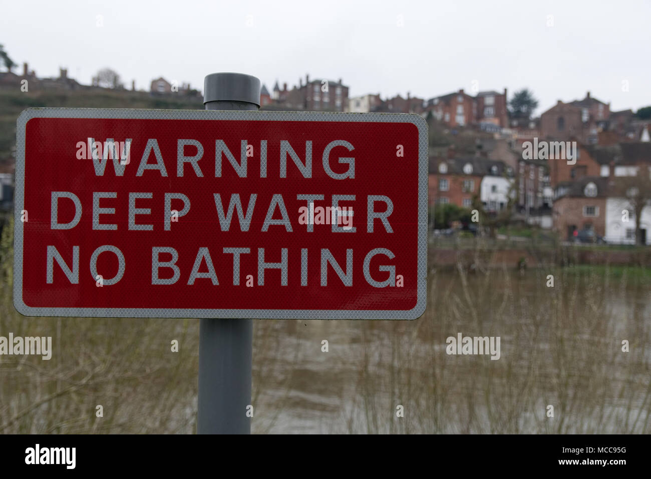 Avvertenza, acqua profonda nessun segno di balneazione. Rettangolare rossa e segno bianco sul palo metallico con il fiume e la città di Bridgnorth, Staffordshire, Inghilterra, in background Foto Stock