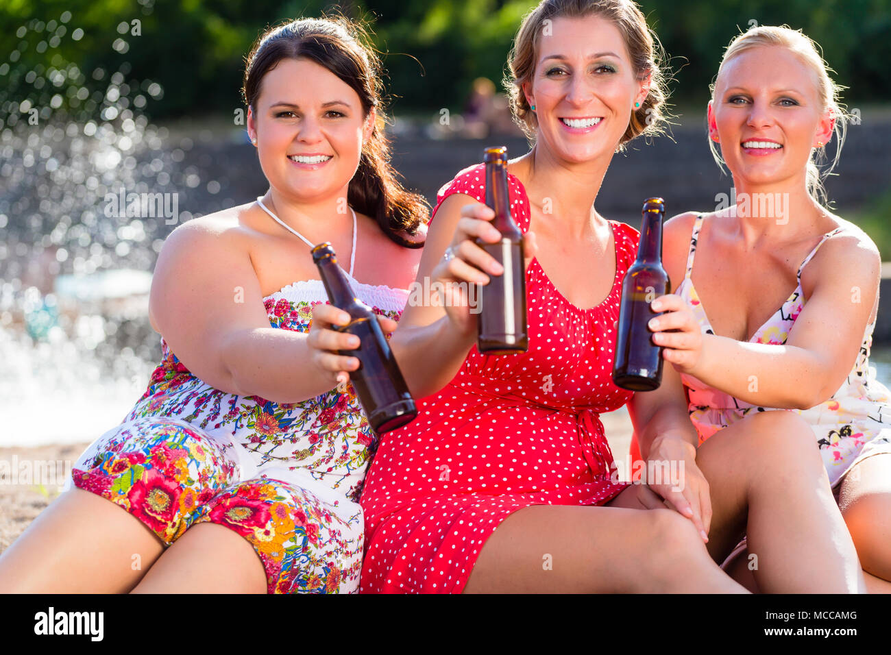 Gli amici a bere birra al fiume beach Foto Stock