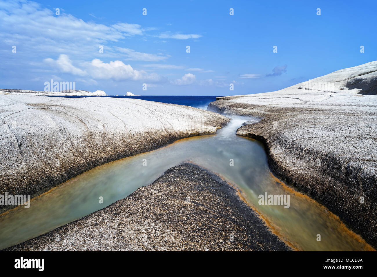 Su una spiaggia bianca di pietra pomice fluisce da due fossati insieme nel mare, al di sopra di un cielo azzurro con poche nuvole sorprendente - Location: Grecia, CICLADI Foto Stock