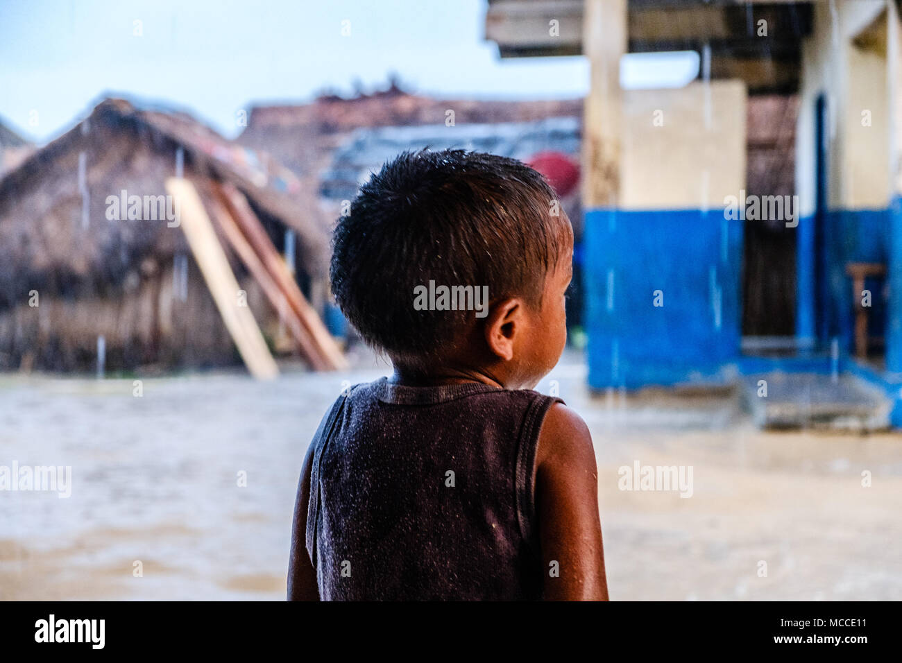 Povero ragazzo soaking wet sul giorno di pioggia da dietro - Foto Stock