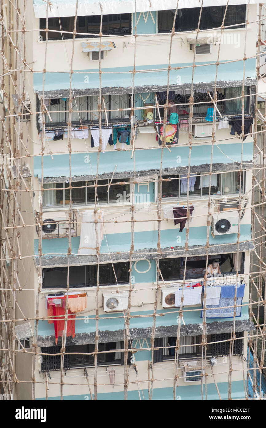 Costruttori la riparazione di un edificio utilizzando indiani tradizionali impalcature in legno realizzate in pali di legno legati insieme con la corda, Malabaresi, Mumbai, India Foto Stock