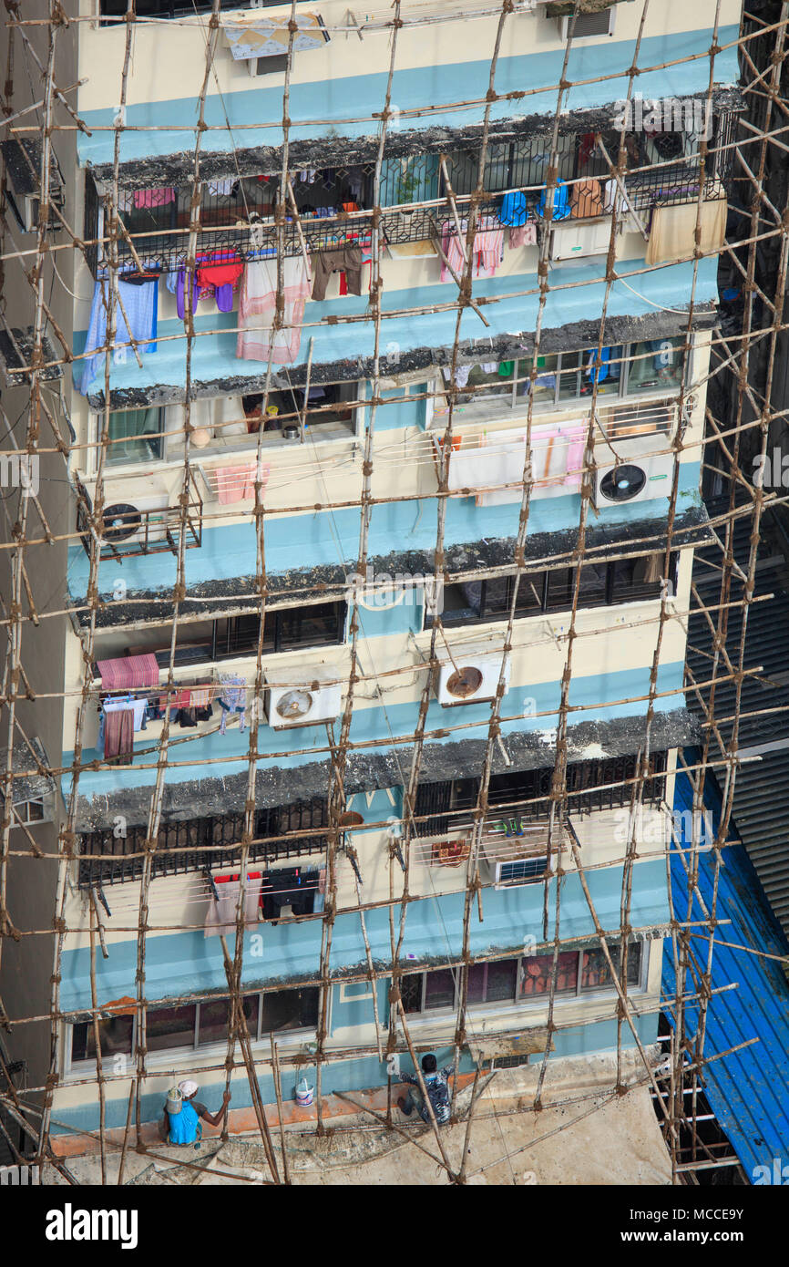Costruttori la riparazione di un edificio utilizzando indiani tradizionali impalcature in legno realizzate in pali di legno legati insieme con la corda, Malabaresi, Mumbai, India Foto Stock
