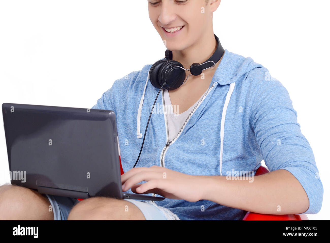 Chiusura del giovane uomo seduto in rosso pouf utilizzando laptop. Il concetto di istruzione Foto Stock