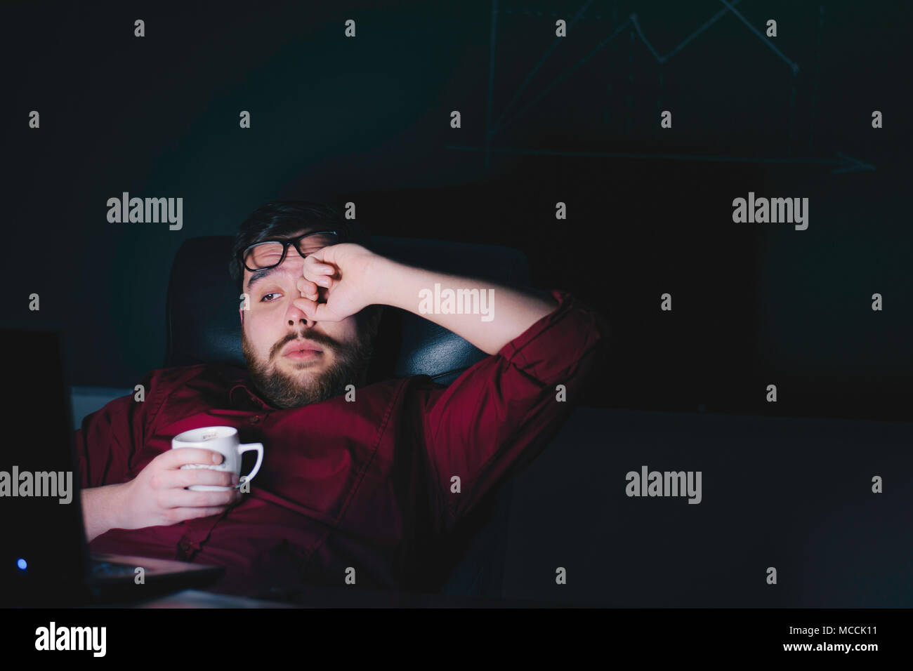 Nsi / Serbia - 04/11/2018: stanco lavoratore di ufficio seduti davanti a un computer portatile durante la tarda ore. Foto Stock