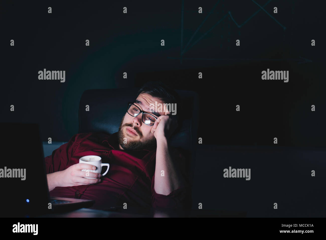 Nsi / Serbia - 04/11/2018: stanco lavoratore di ufficio seduti davanti a un computer portatile durante la tarda ore. Foto Stock