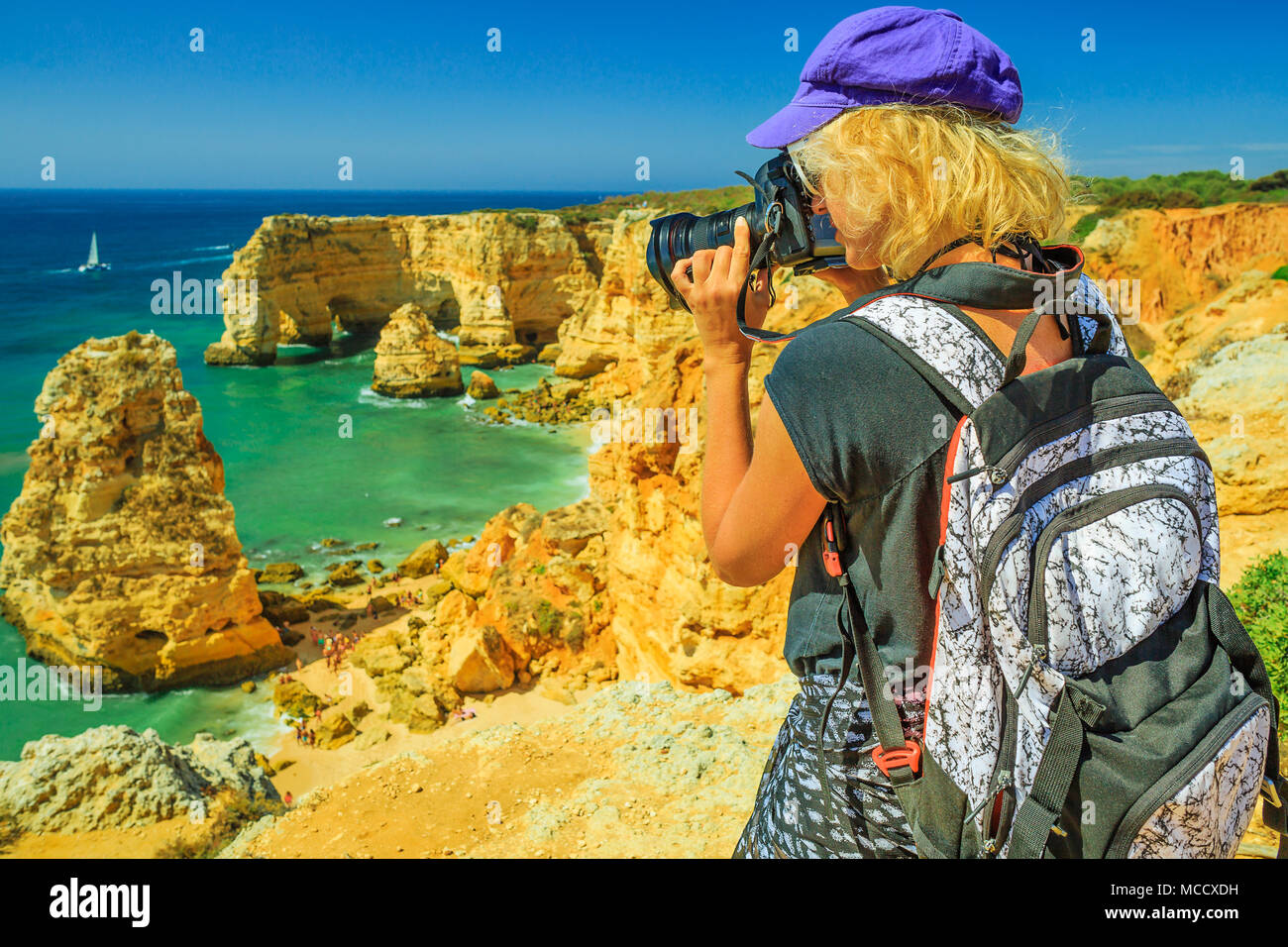 Viaggi fotografo prende shot iconica archi naturali di Praia da Marinha in Algarve. Turista femminile scatta foto con la fotocamera professionale di alte scogliere di popolari Marinha Beach. Viaggio in Portogallo Foto Stock