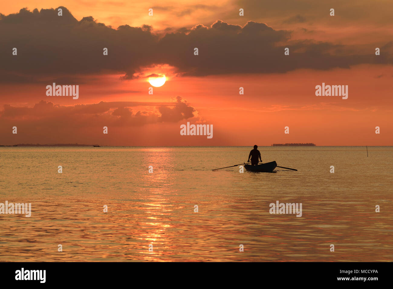 Silhouette attività di pescatori in mare contro il tramonto - Bintan Island, Indonesia Foto Stock