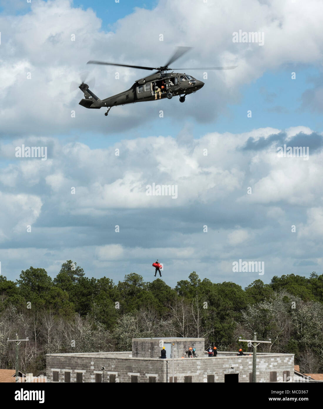 Emerson Kovalanchik, S.C. Elicottero di salvataggio acquatico Team, pende da una UH-60 Black Hawk all approccio per simulare un punto di salvataggio di articolazione durante il salvataggio in elicottero il paranco la formazione con società Alfa, 1-111esimo battaglione aviazione, S.C. La guardia nazionale durante il Patriot Sud 2018, Camp Shelby, Hattiesburg, Miss., Feb 15, 2018. PATRIOT è un nazionale di formazione operativa esercizio sponsorizzato da La Guardia nazionale che mira ad aumentare la comprensione del coordinamento, le politiche e le procedure necessari a condurre una Joint Inter-Agency risposta domestico. (U.S. Air National Guard photo by Staff Sgt. Mic Foto Stock