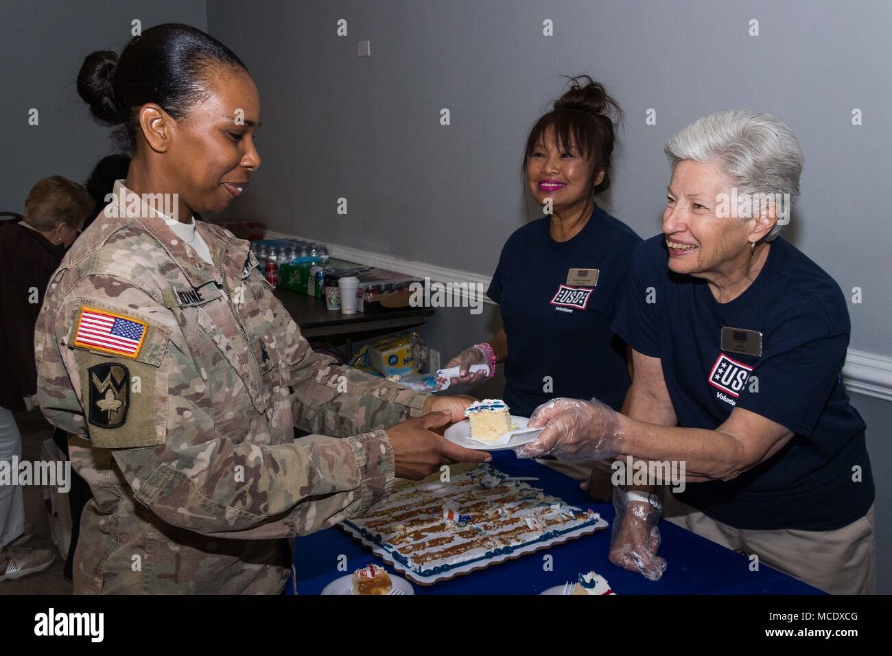 Un volontario da Stati Uniti d'oltremare Florida Centrale Capitolo mani una fetta di torta di U.S. Army Sgt. Nicole Browne, sede e Sede Società, 143d supporto comando (Expeditionary), durante una cerimonia di distribuzione condotto nel febbraio 24, 2018 il Clarion Inn in Orlando, Florida membri da OSU Central Florida fornito torta, spuntini e rinfreschi per le centinaia di soldati e membri della famiglia che hanno partecipato all'evento. La cerimonia ha onorato Browne e circa 200 dei suoi compagni soldati dal 143d comitato che si prestarono a lasciare i loro amici e cari per imbarcarsi su un anno-lon Foto Stock