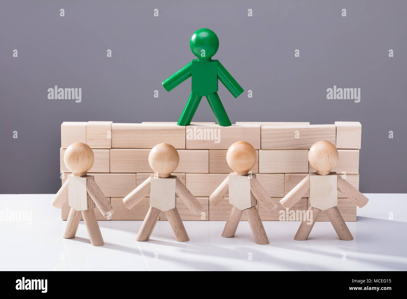 Fila di figure di fronte la Figura in piedi sulla parte superiore dei blocchi di legno Foto Stock