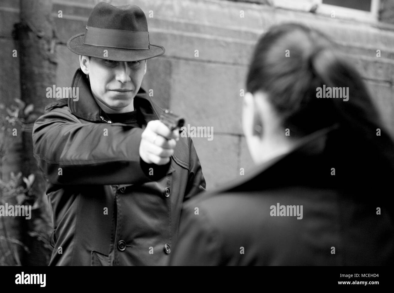 Ritratto monocromatica dell'uomo minaccia la donna con una pistola Foto Stock