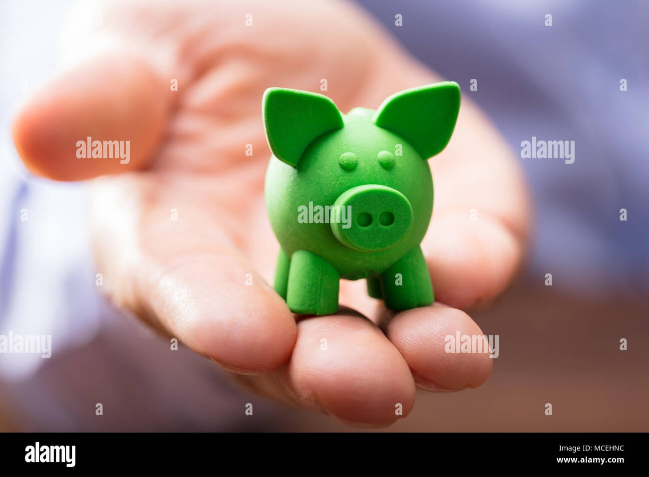 Close-up di verde poco Piggybank sulla persona della mano Foto Stock