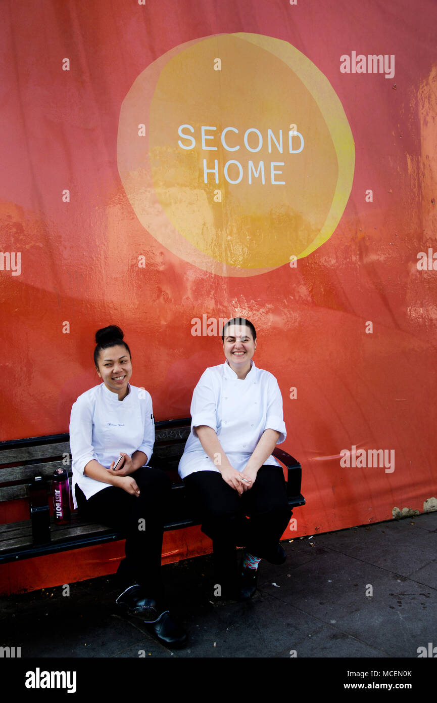 Hackney, Londra. Il personale del ristorante, dal Brasile e dalla Francia, hanno una pausa sotto un cartello che diceva "seconda casa". Foto Stock