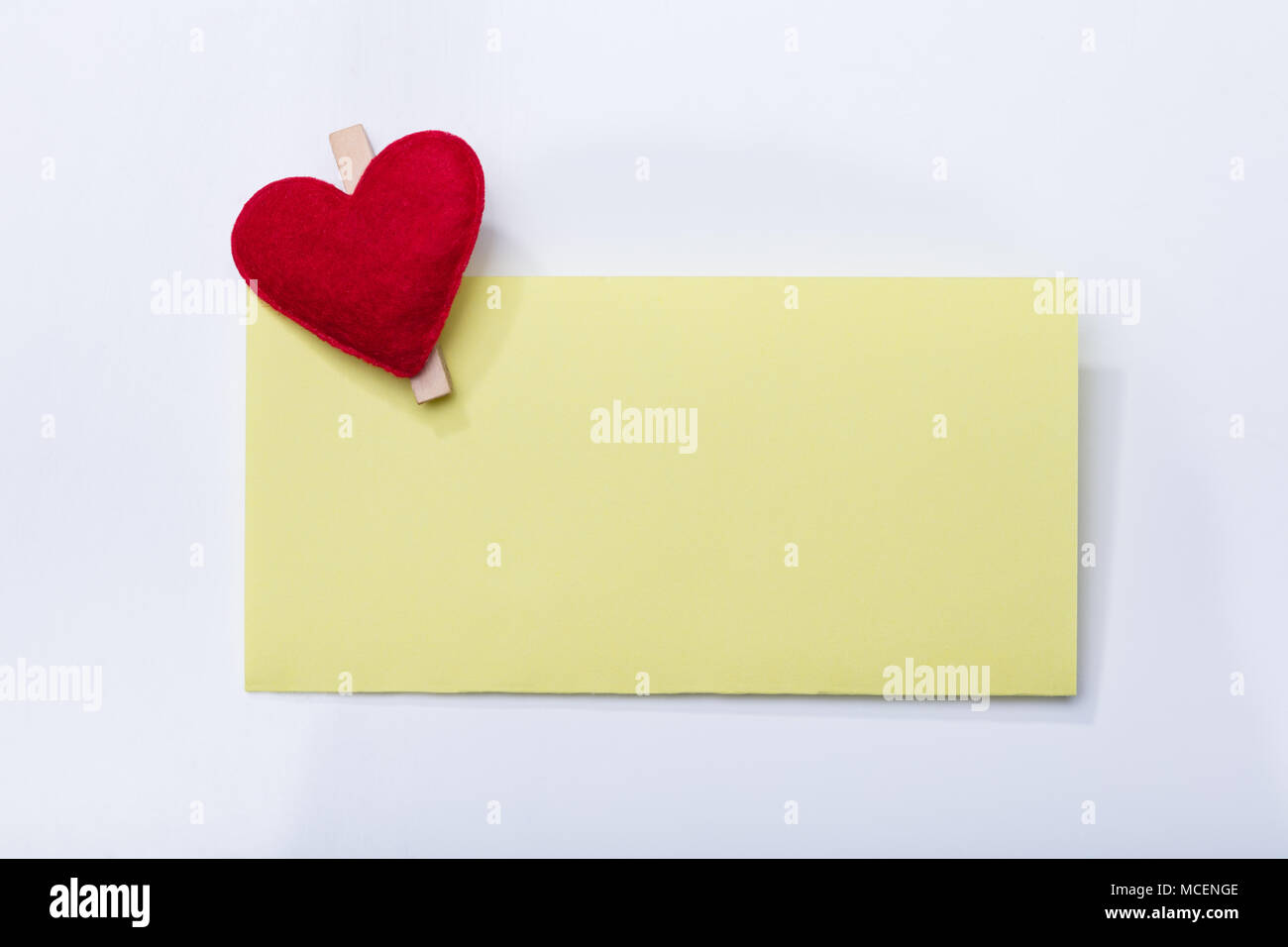 Vista in elevazione dello sbozzato cartellino giallo con cuore Clothespin su sfondo bianco Foto Stock