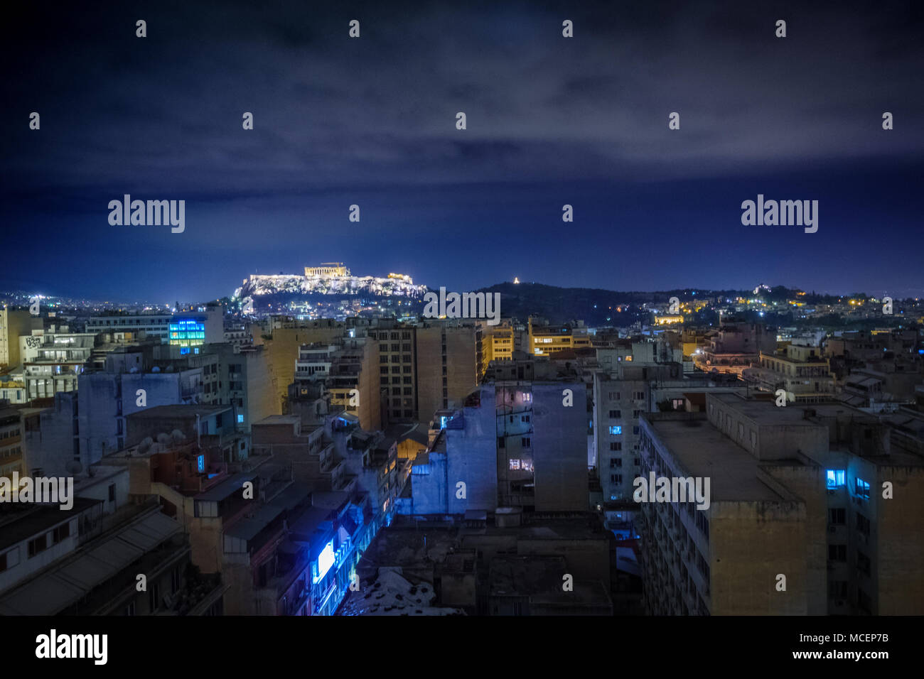 Edifici residenziali con illuminata antiche rovine in background, Atene, Grecia Foto Stock
