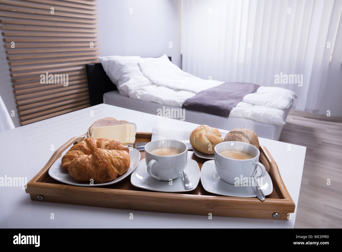 Cornetti freschi e la tazza di tè nel vassoio in legno a colazione Foto Stock