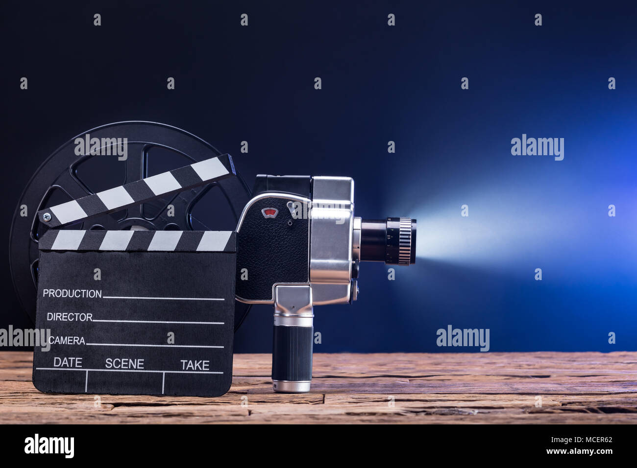 Close-up di un illuminato Movie Camera con bobina di pellicola e il battaglio Board sulla scrivania in legno Foto Stock