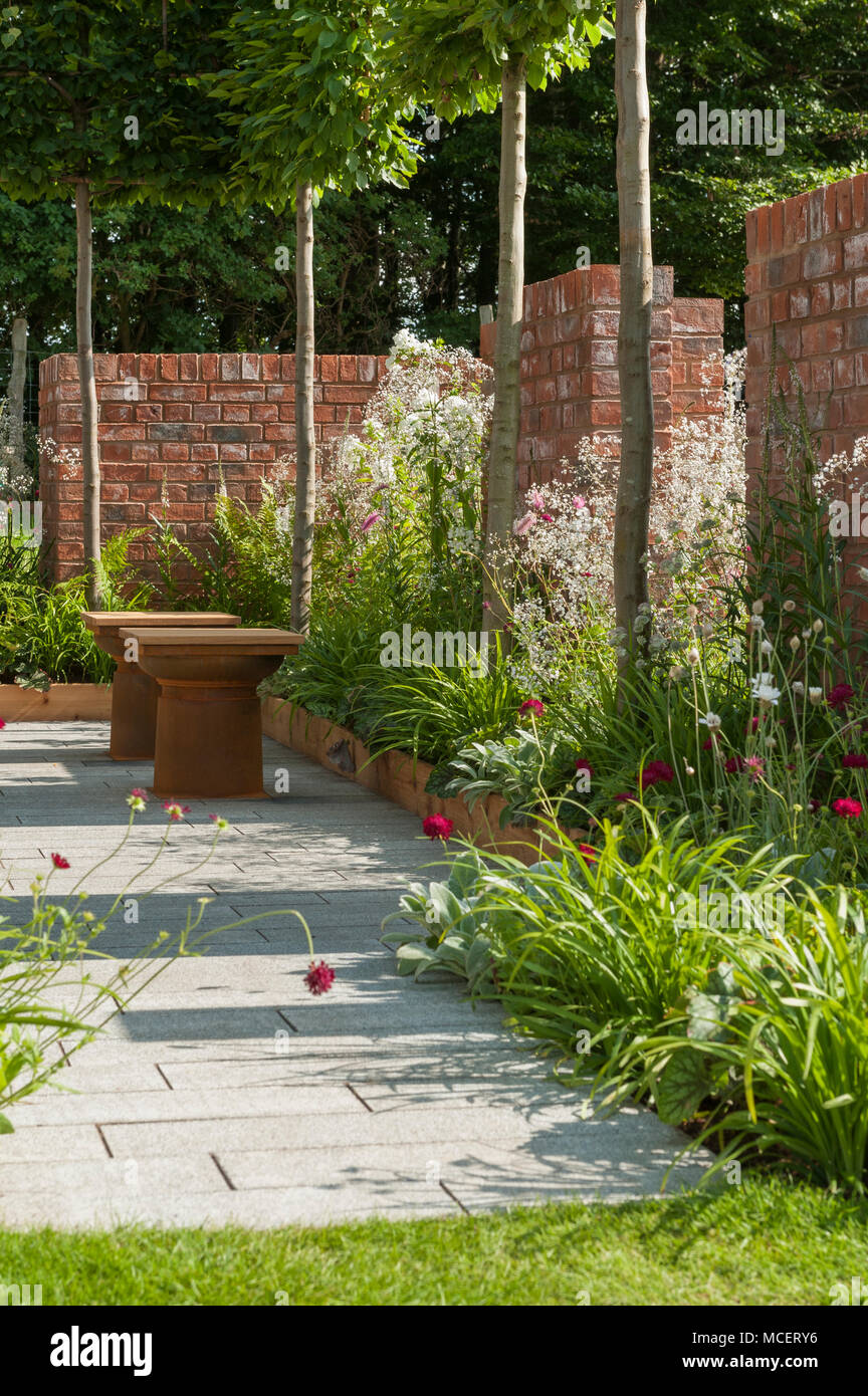 Pleached alberi, la fioritura delle piante di confine & frammentata di pareti in mattoni in show garden - "l'Albert Dock giardino,' RHS Flower Show, Tatton Park, Inghilterra, Regno Unito. Foto Stock