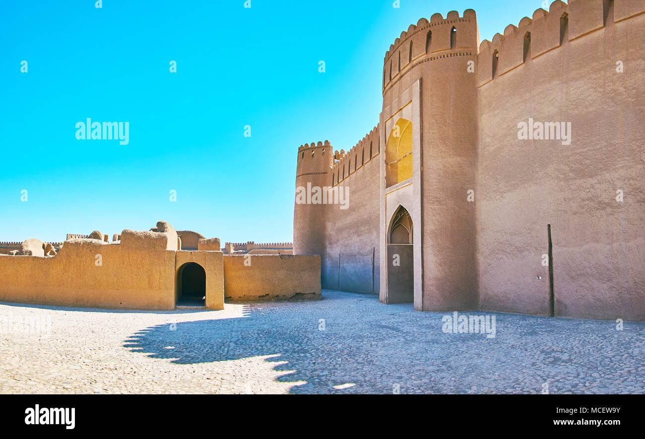 La parete di facciata del castello di Rayen con gate, osservando la terrazza e le rovine di antichi edifici residenziali di fronte ad esso, l'Iran. Foto Stock