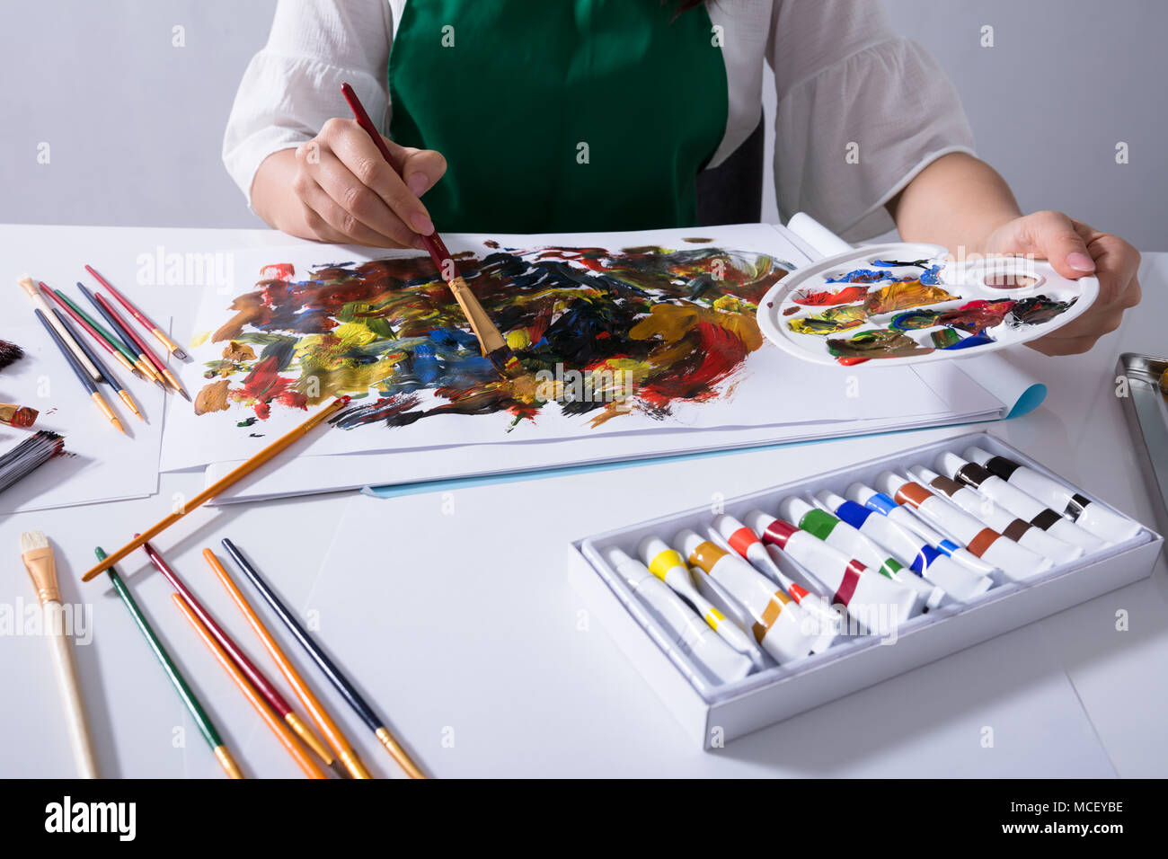 Close-up di un artista femminile la mano che tiene la palette di vernice mentre la pittura su tela carta Foto Stock