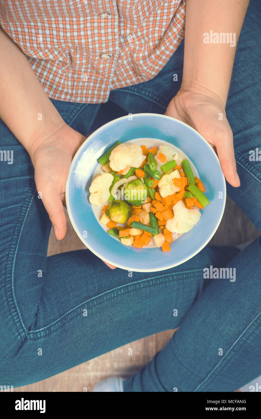 Ragazza con un piatto di verdura in mani. Mangiare sano concetto. Una corretta alimentazione. Cibo vegetariano. I vegani cibo. Tonica immagine. Foto Stock